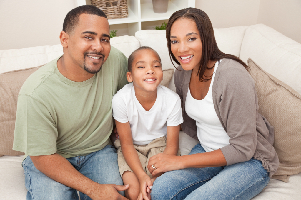 A happy African American man, woman and boy, father, mother and son, family sitting together at home